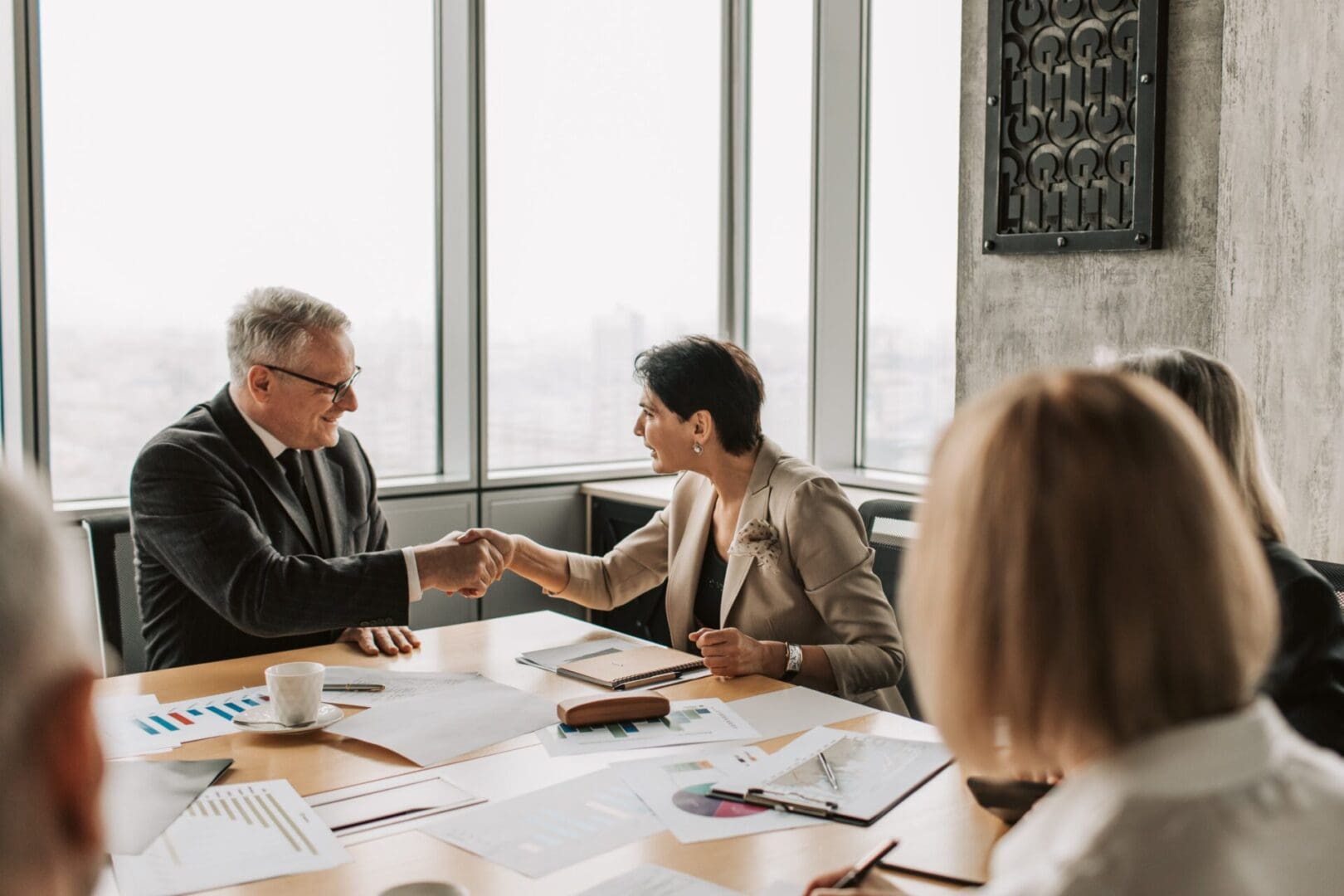 A man and woman shaking hands over a table.