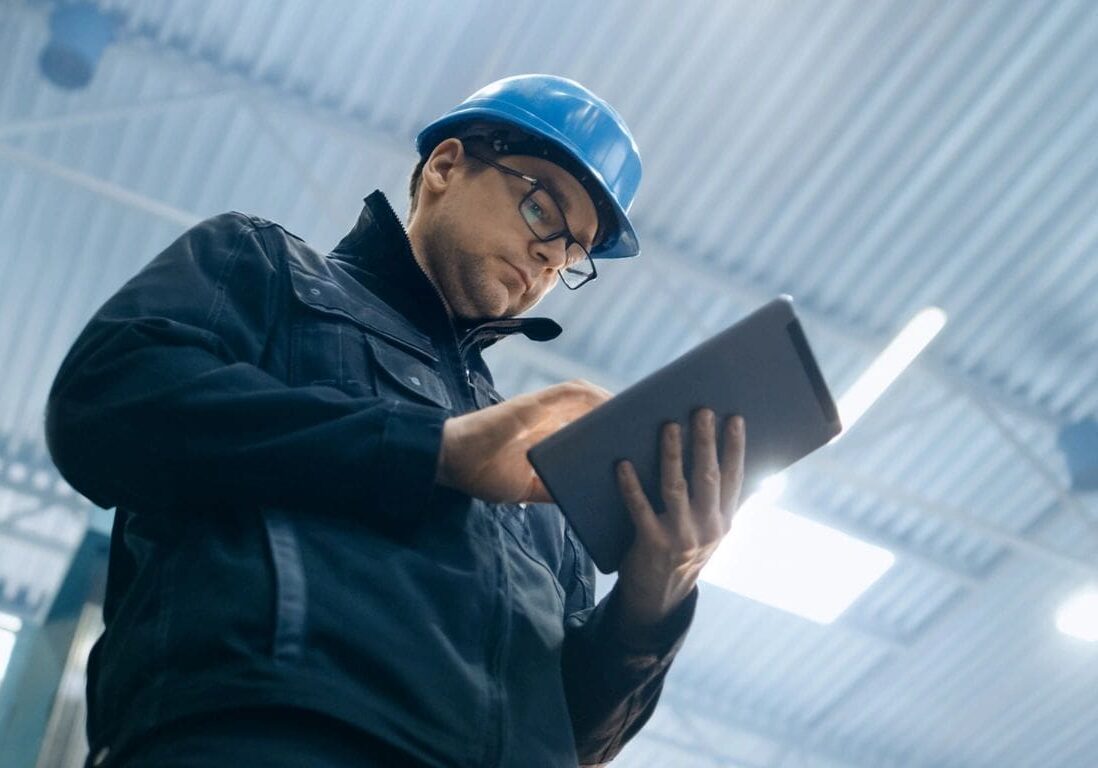 A man in a hard hat using a tablet.