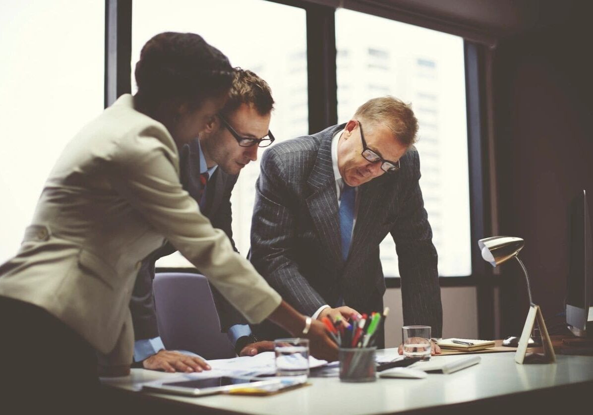 Three men in suits and ties working on papers.