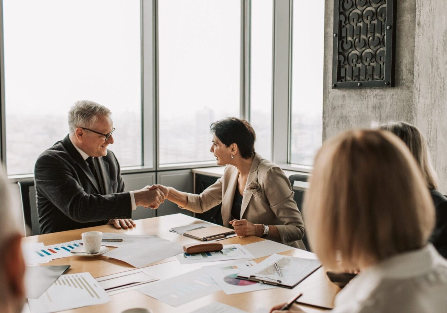 A man and woman shaking hands over a table.